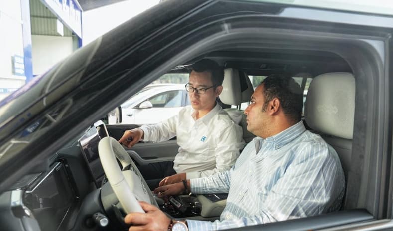 Two people reviewing vehicle controls inside a vehicle